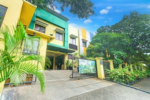 A multi-story building with a gated entrance, potted plants, and a clear sky. - Hotel O Tebet Near Tebet Station (Jakarta)