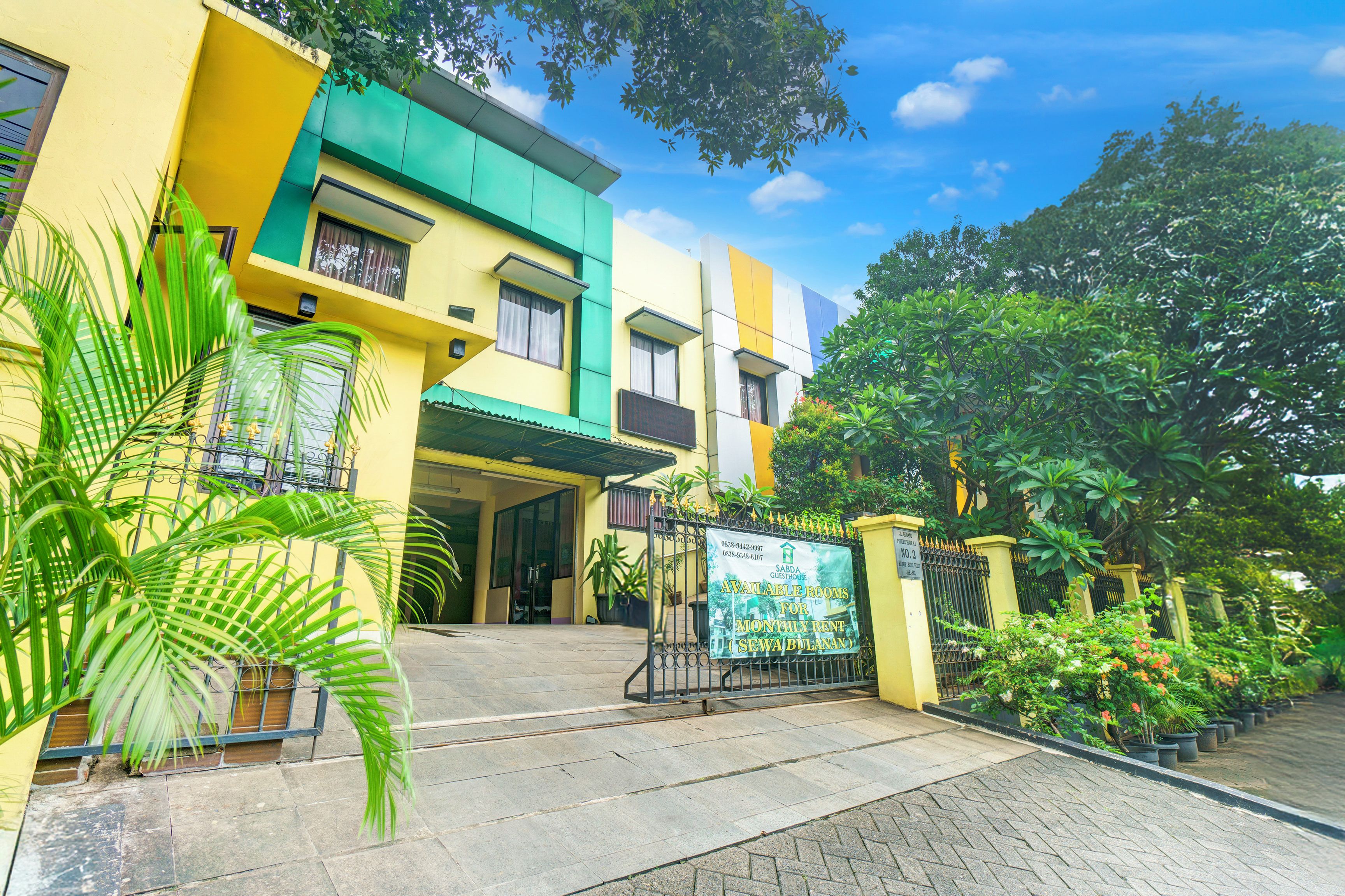 A multi-story building with a gated entrance, potted plants, and a clear sky.