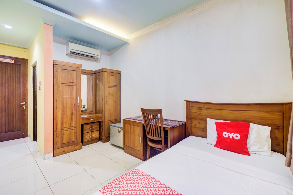 Quarto com cama, escrivaninha, cadeira, armários de madeira e ar condicionado.