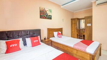 Ein Hotelzimmer mit zwei Betten, jeweils mit roter und weißer Bettwäsche, einem Holz-Kopfteil und einem Gemälde an der Wand.