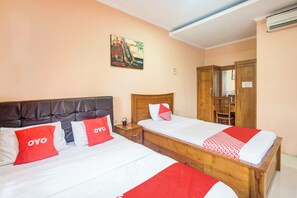 Habitación de hotel con dos camas, cada una con ropa de cama roja y blanca, cabeceros de madera y un cuadro en la pared.