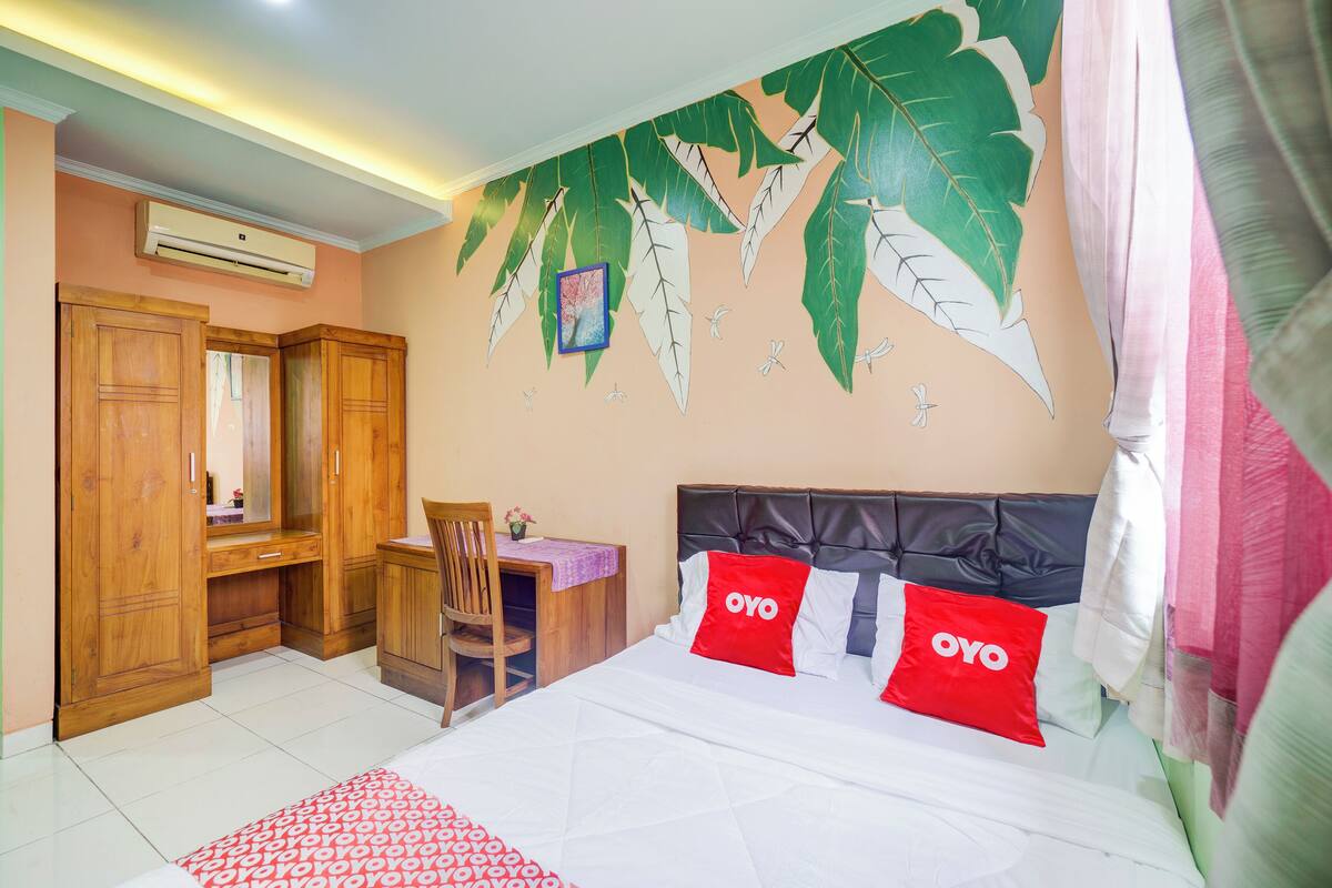 A bedroom with a bed, a desk, and a chair.