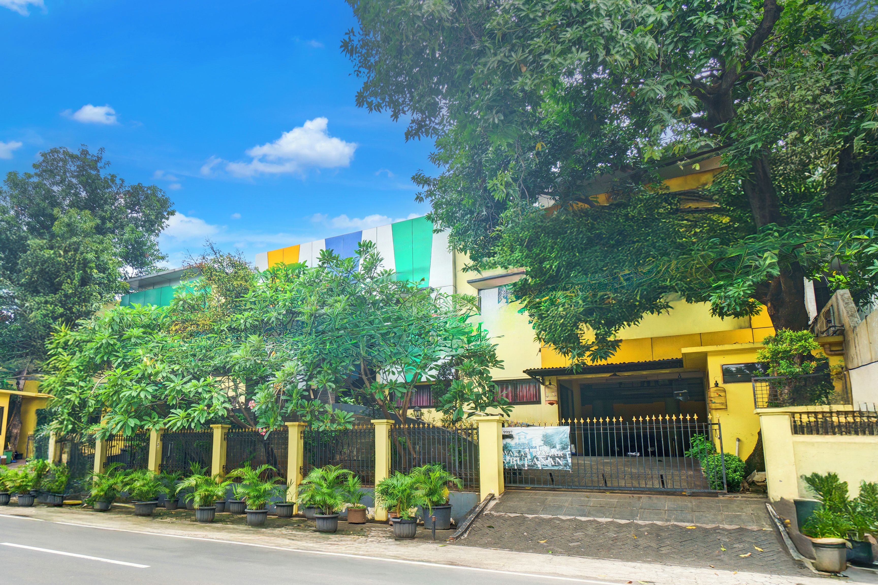 Un edificio residencial con entrada porticada, plantas en macetas y cielo despejado.