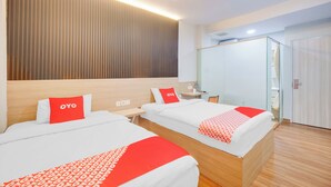 A hotel room with two beds, each with a red and white patterned bedspread, a wooden headboard, and a wall-mounted light fixture. - Hotel O Tanjung Duren Near Mall Citraland (Jakarta)