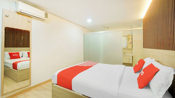 A modern hotel room with a wooden bed, a large mirror, and a wooden wardrobe. - Hotel O Tanjung Duren Near Mall Citraland (Jakarta)