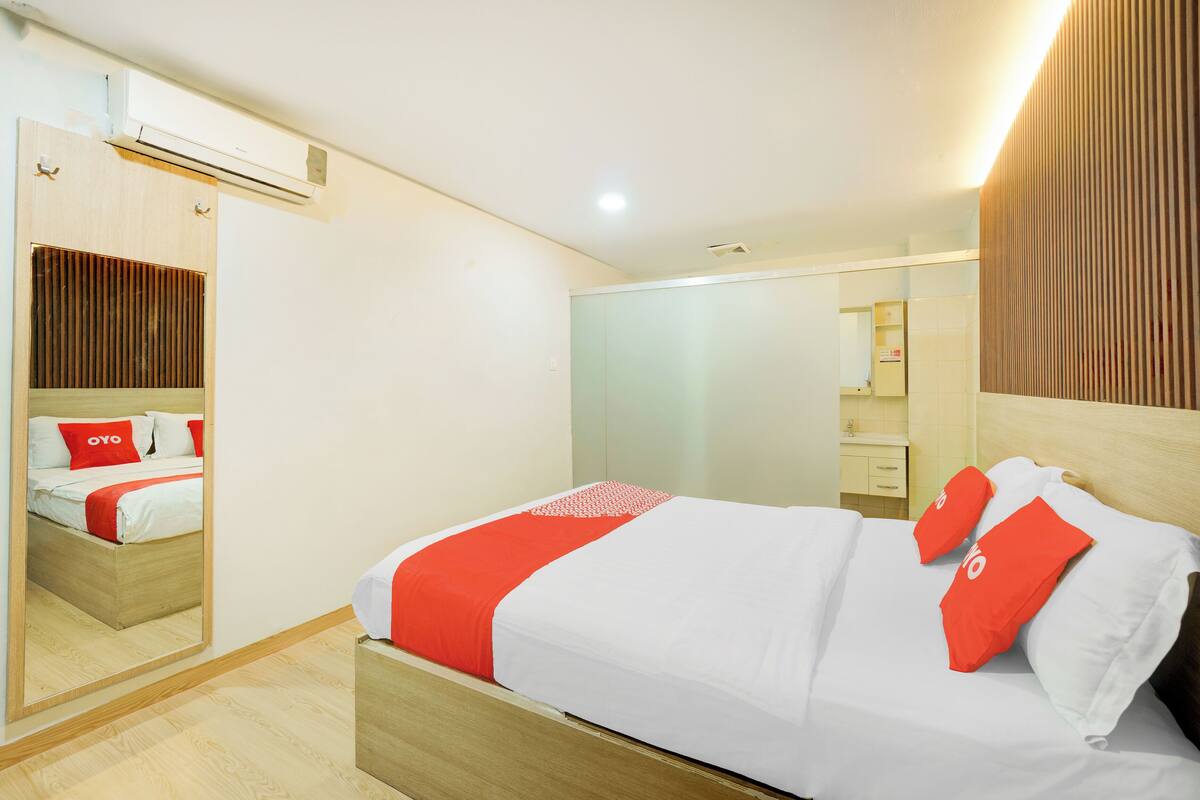 Ein modernes Hotelzimmer mit einem hölzernen Bett, einem großen Spiegel und einem Holzschrank.