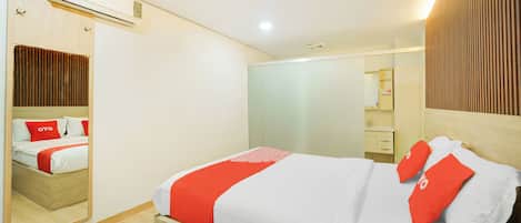 Een moderne hotelkamer met een houten bed, een grote spiegel en een houten garderobe.