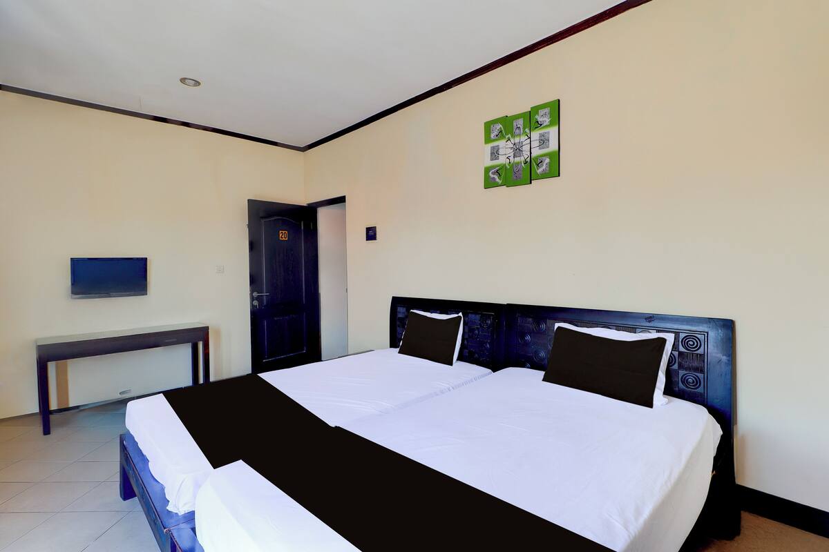 A hotel room with a large bed, a desk, and a door.