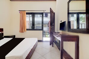 A hotel room with a bed, a TV, a window with curtains, and a view of the outside. - Collection O Near Bali Royal Hospital Renon (Denpasar)
