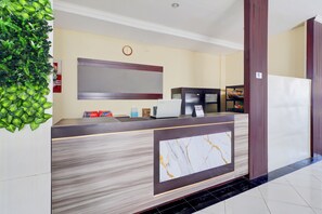 Una recepción con detalles de mármol, un reloj en la pared y una decoración verde.