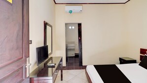 A hotel room with a bed, a desk with a TV, a wardrobe, and a bathroom visible through an open door. - Collection O Near Bali Royal Hospital Renon (Denpasar)