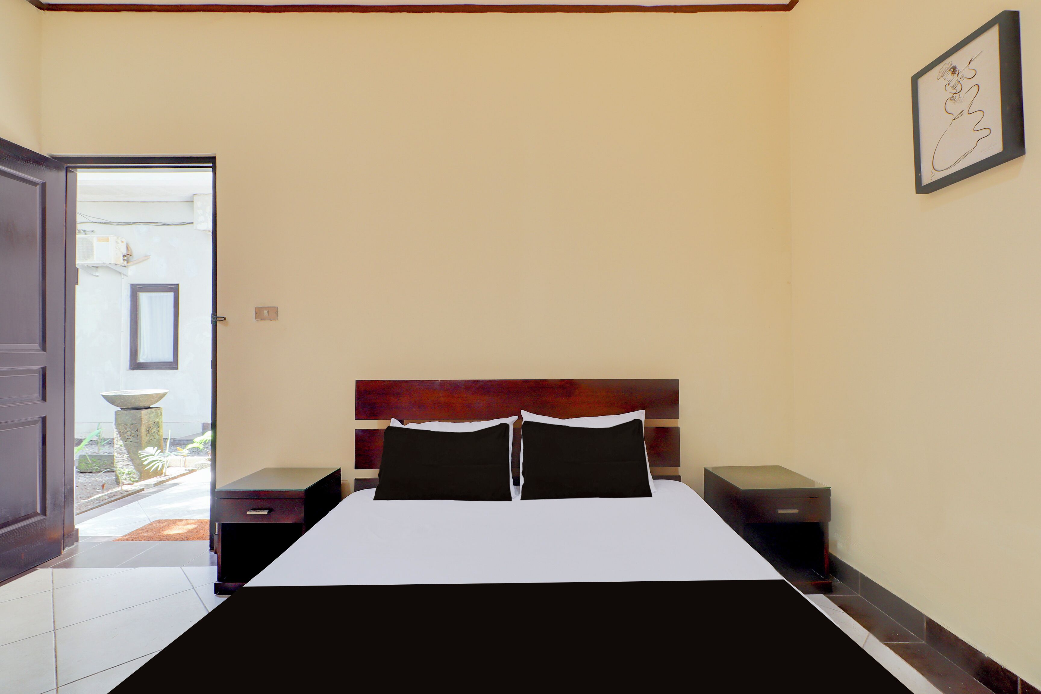 Ein Schlafzimmer mit einem Bett, zwei Nachttischen, einer Tür zum Balkon und einem gerahmten Bild an der Wand.
