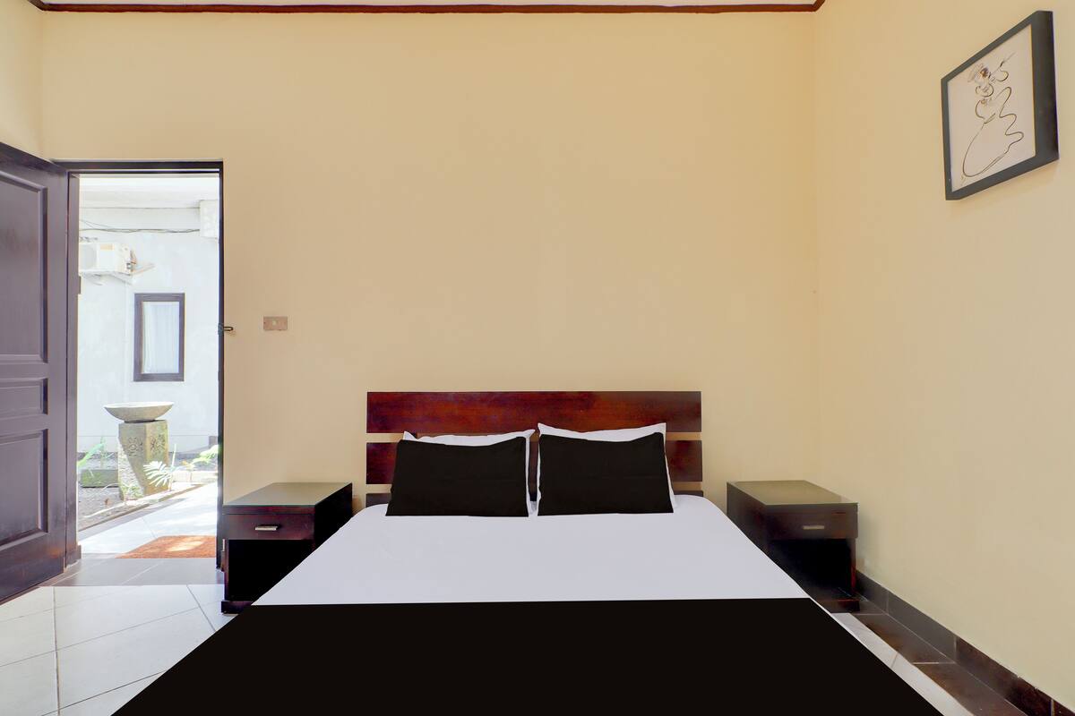 A bedroom with a bed, two bedside tables, a nightstand, a door to a balcony, and a framed picture on the wall.