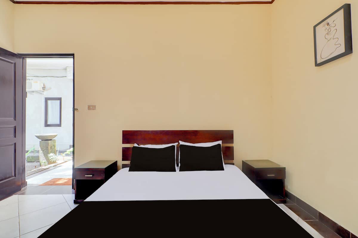 Ein Schlafzimmer mit einem Bett, zwei Nachttischen, einer Tür zum Balkon und einem gerahmten Bild an der Wand.