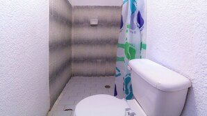 A small bathroom with a white toilet, a shower curtain, and a tiled floor. - Collection O Near Bali Royal Hospital Renon (Denpasar)