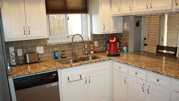 A kitchen with white cabinets, a granite countertop, a dishwasher, a coffee maker, and a window with blinds. - Cozy Court House near Flower Mound and Lewisville (Flower Mound)