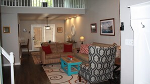 A living room with a sofa, armchair, coffee table, and a staircase leading to an upper level. - Cozy Court House near Flower Mound and Lewisville (Flower Mound)