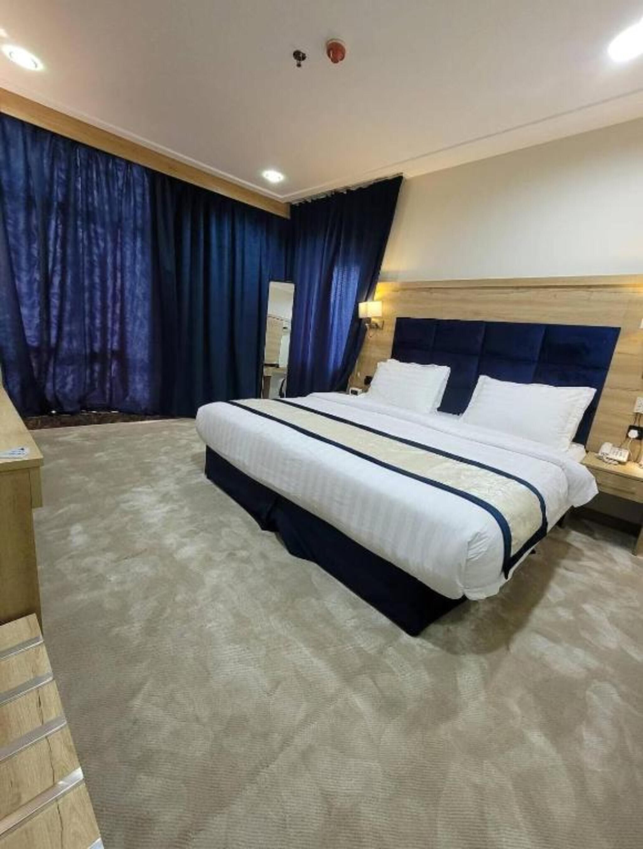 Una habitación de hotel con una cama grande, un cabecero de madera, una mesita de noche y un espejo.