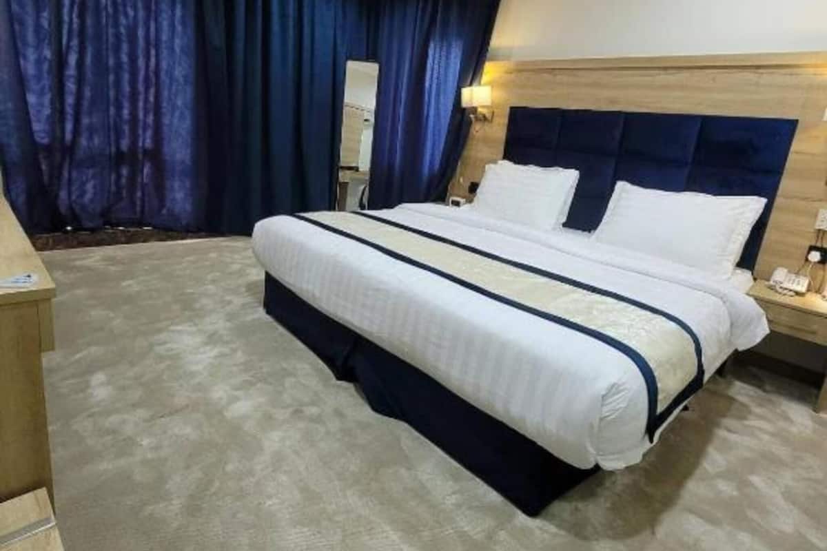Una habitación de hotel con una cama grande, un cabecero de madera, una mesita de noche y un espejo.