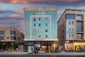 A multi-story building with a central entrance, signage for 'Gardenia Park' and 'Graffol,' and several parked cars in front. - Gardenia Park Al Zaharaa (Jeddah)