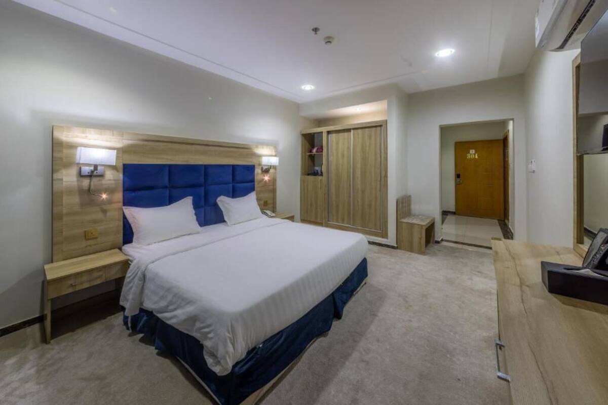 Una habitación de hotel con cama, mesitas de noche, armario y escritorio.