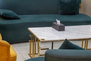 A modern living room with a green sofa, a marble coffee table, and a yellow armchair. - Gardenia Park Al Zaharaa (Jeddah)