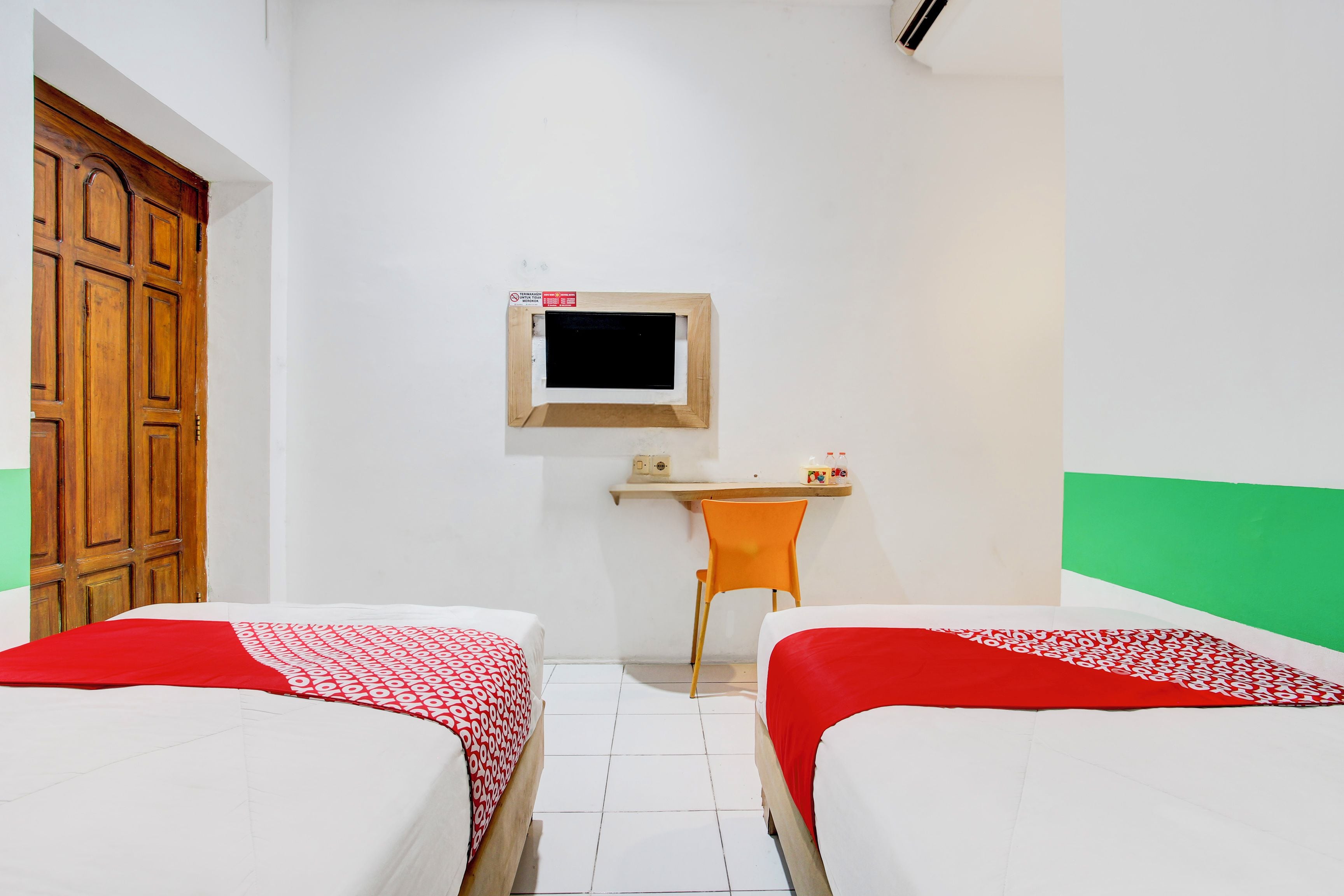Une chambre avec deux lits, un bureau, une chaise et une petite fenêtre.
