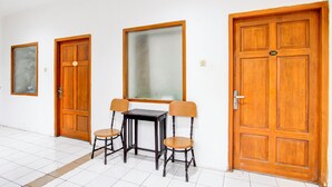 A room with a wooden door, a large mirror, a small table, and two chairs. - Collection O Jalan Slamet Riyadi Kampung Batik K (Surakarta)
