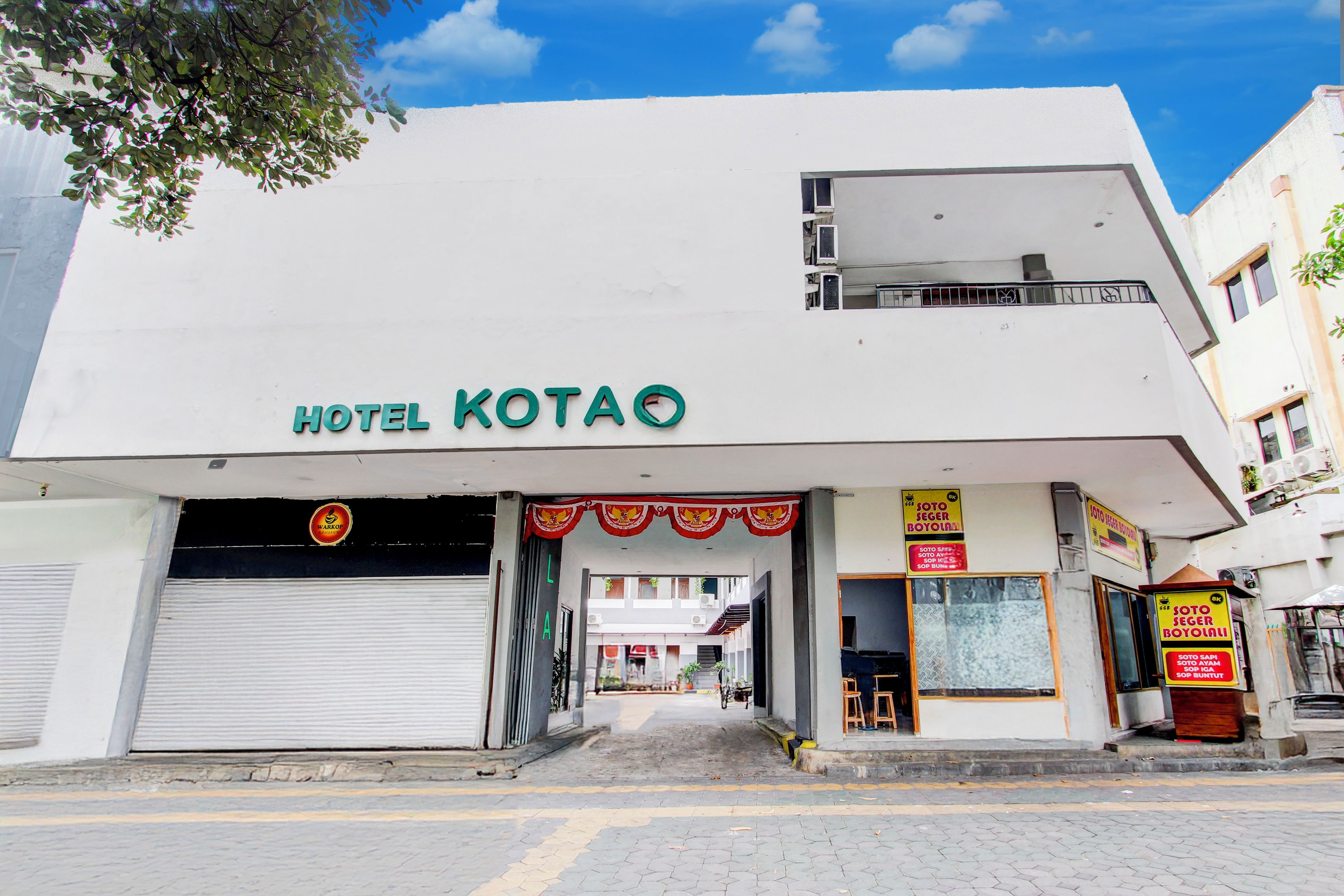 A hotel named 'HOTEL KOTAO' with a visible entrance, a closed garage door, and a signboard advertising 'SOTO SERGER BOYOLALI'.
