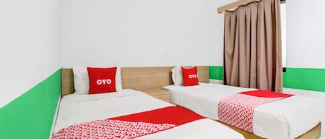 A room with two beds, each with a red and white patterned bedspread, and matching red pillows.