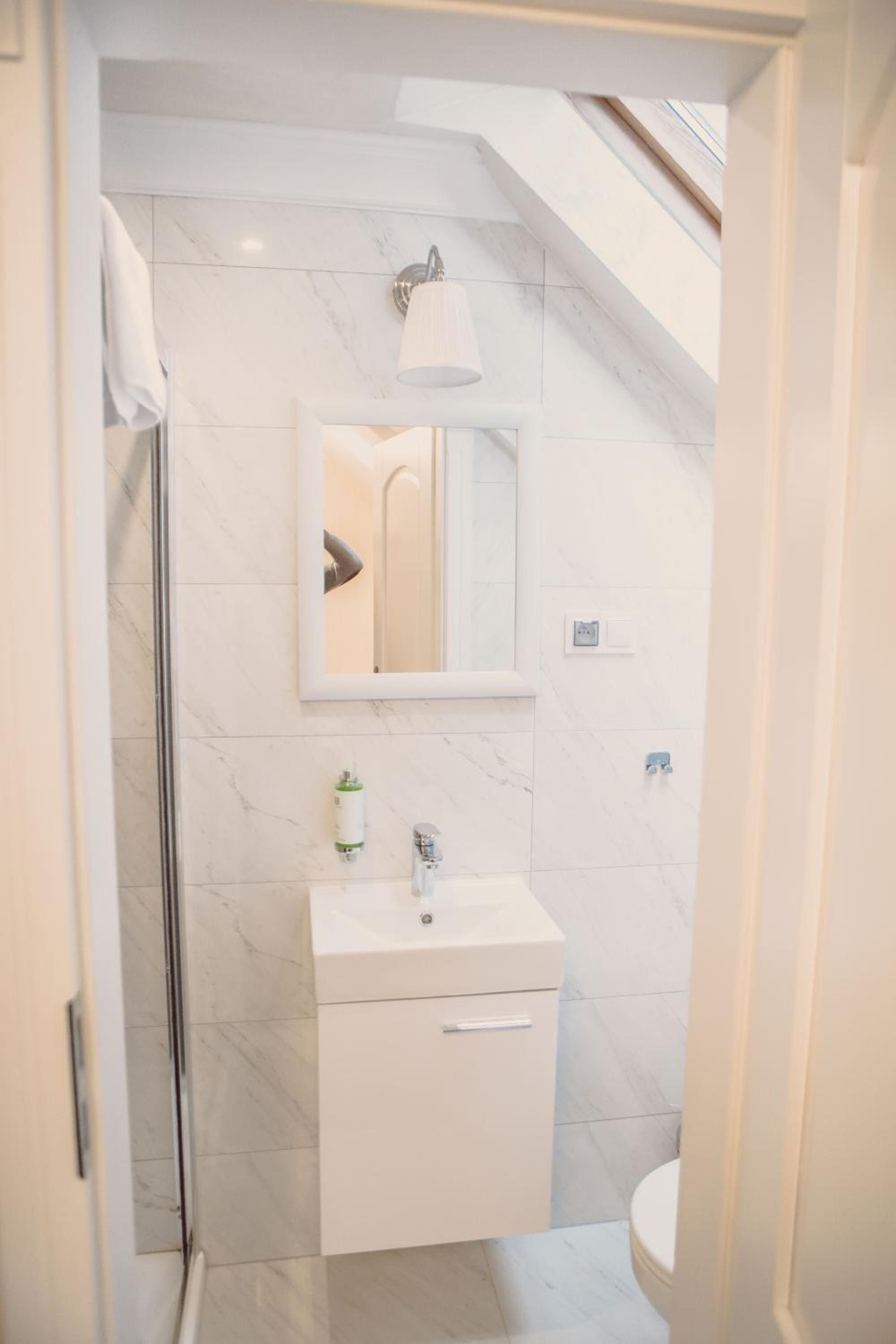A modern bathroom with a white vanity, a mirror, and a shower.