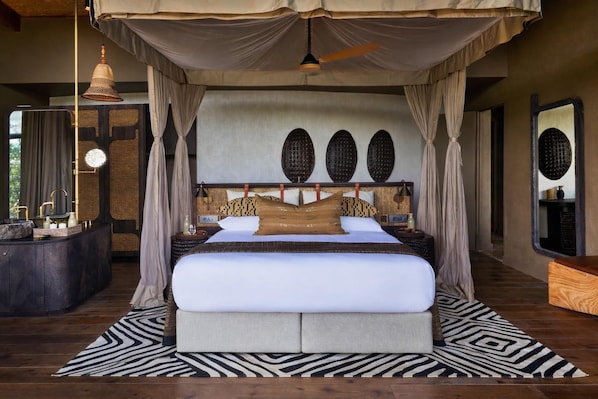 A large bed with a canopy, a round wall clock, and a large mirror. - Bupenyu Luxury Boutique Lodge (Matabeleland North)