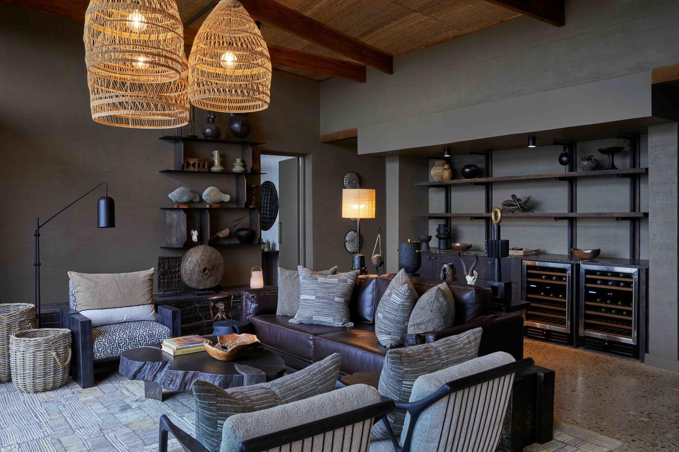 A modern living room with a sofa, armchairs, a coffee table, wicker baskets, a floor lamp, and a wine rack.