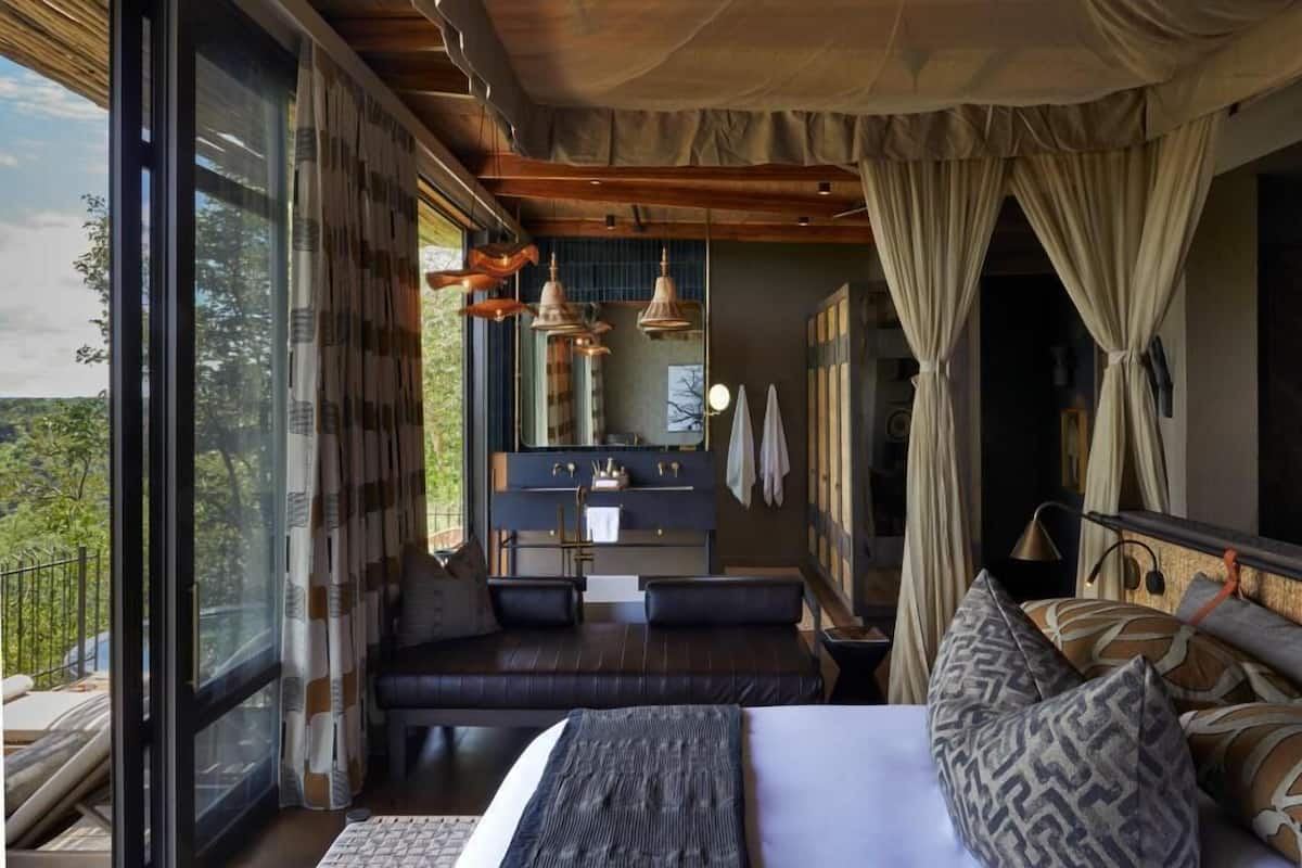 Un dormitorio con una cama grande, un espacio para sentarse, un tocador y vistas al exterior.
