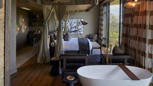 Quarto moderno com uma cama grande, um espaço para sentar, uma banheira e vista para o exterior.