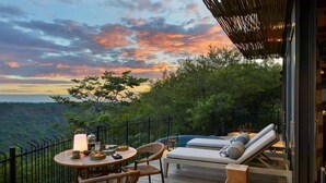 Um terraço com mesa, cadeiras, área de estar e vista para a paisagem.
