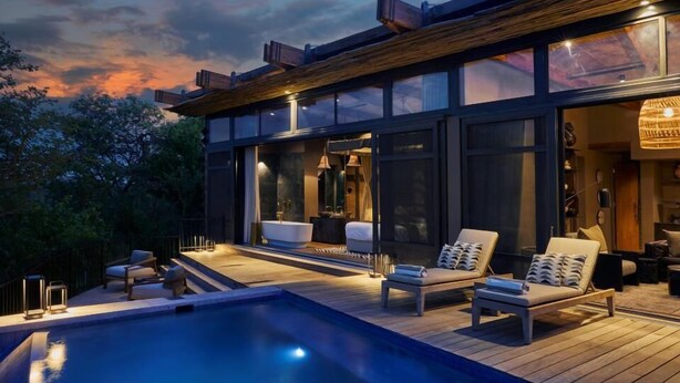 Uma casa moderna com piscina, área de estar externa e uma grande janela com vista para a piscina.