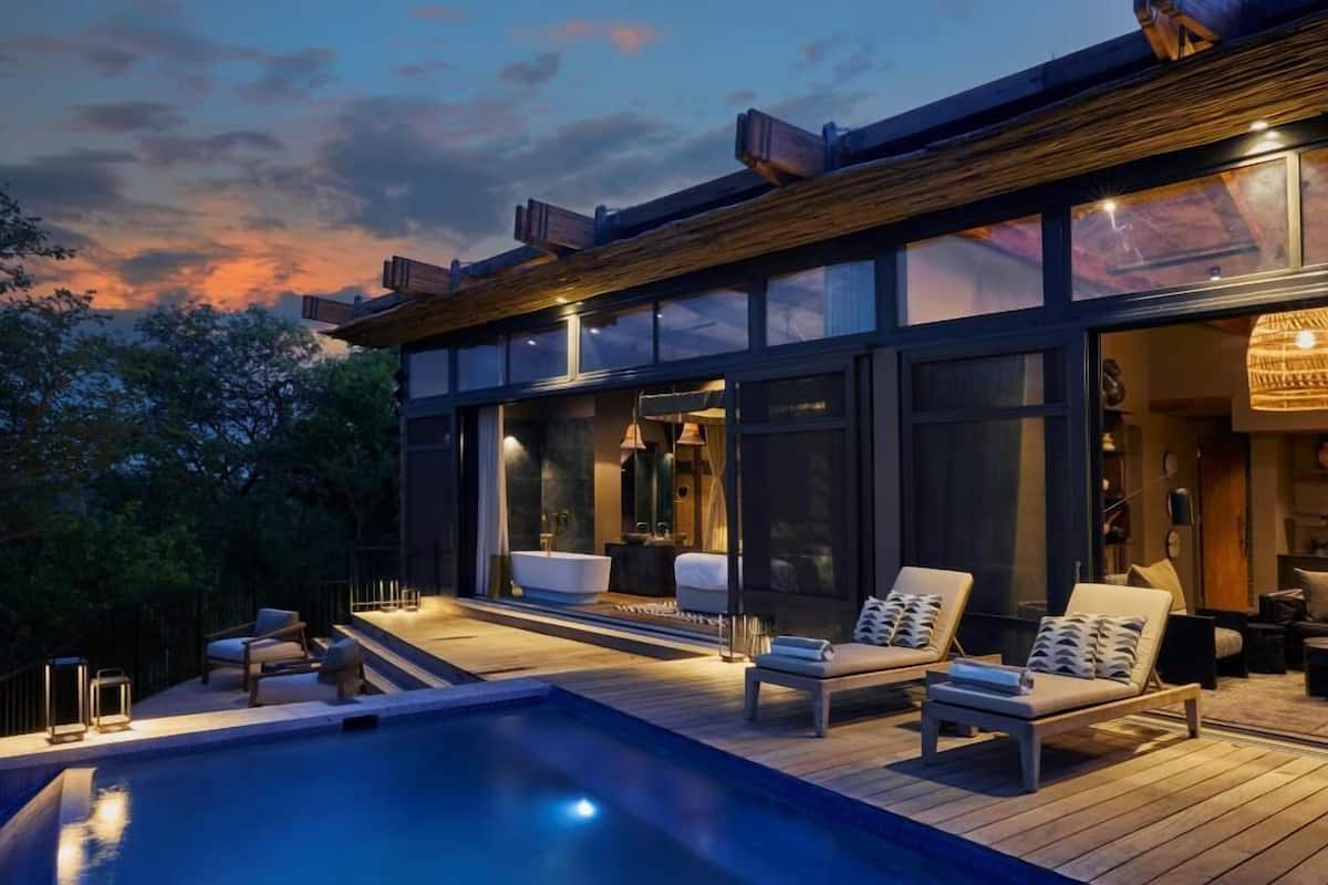 Una casa moderna con piscina, mobiliario exterior y un amplio ventanal con vistas a la piscina.