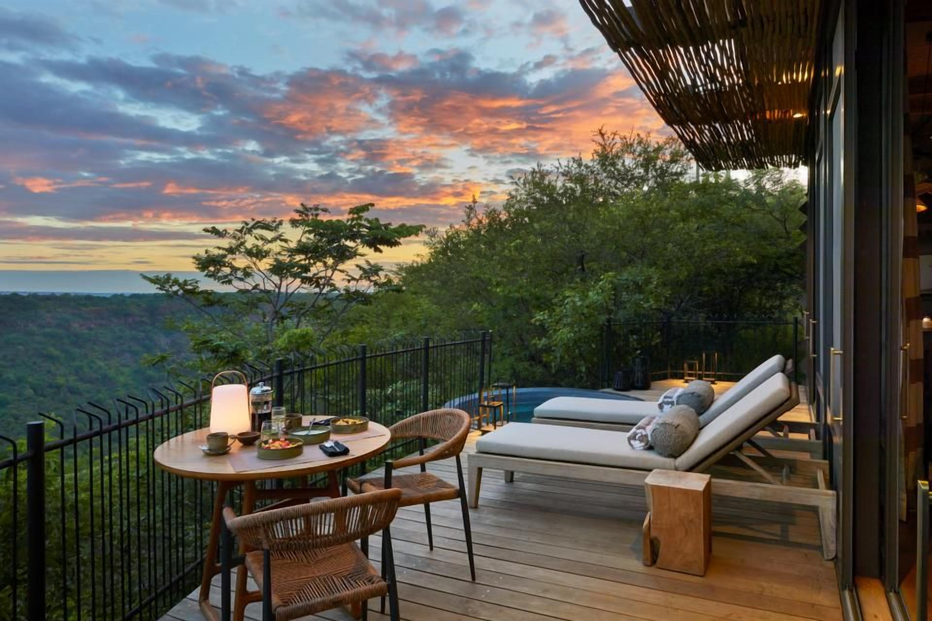A deck with a table, chairs, a lounge area, and a view of the landscape.