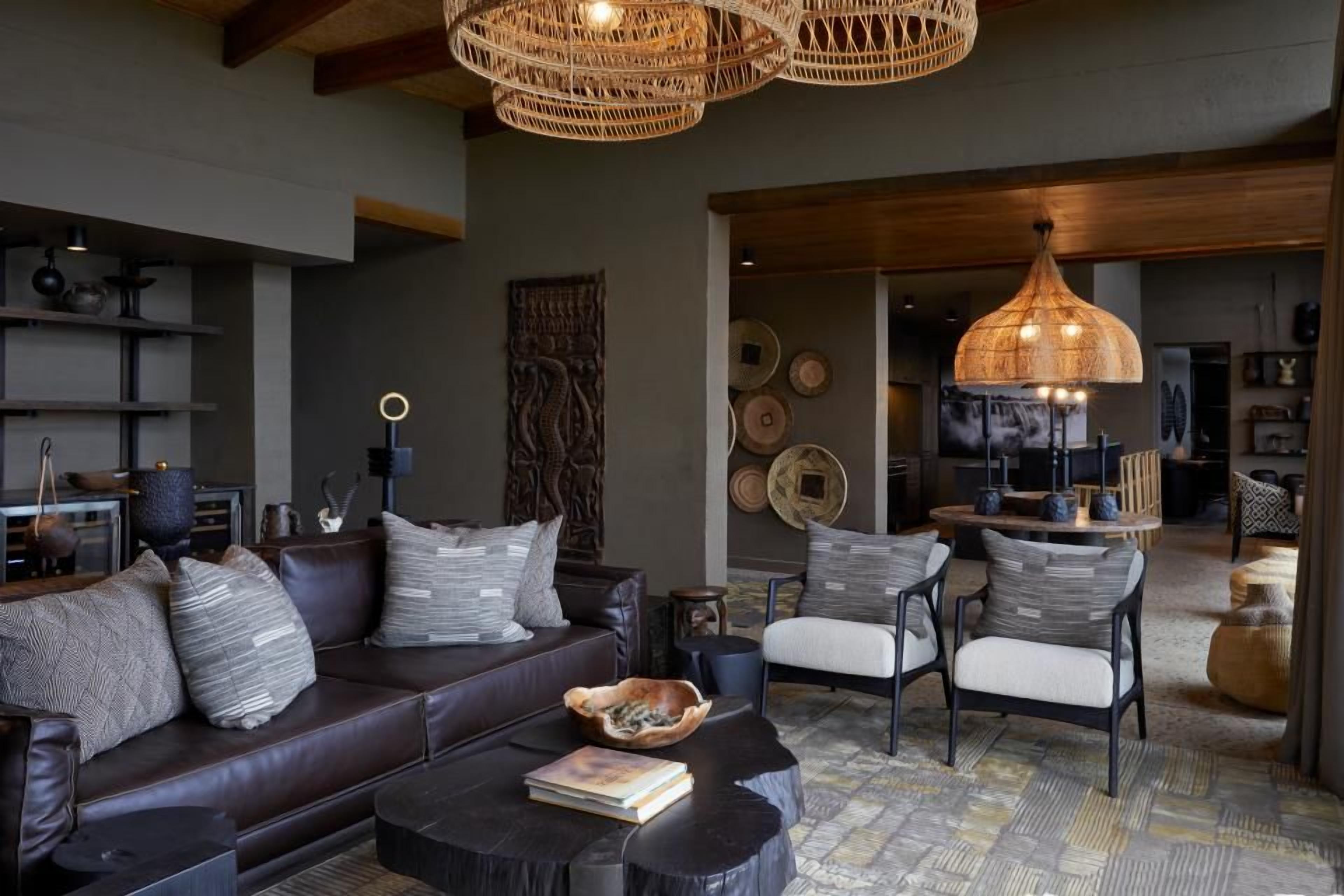 A modern living room with a leather sofa, a round coffee table, and a large woven light fixture.