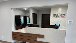 A reception area with a reception desk, two vending machines, and a wall sign for 'Home Towne Studios by RedRoof.' - Hometownestudios Bradenton (Bradenton)