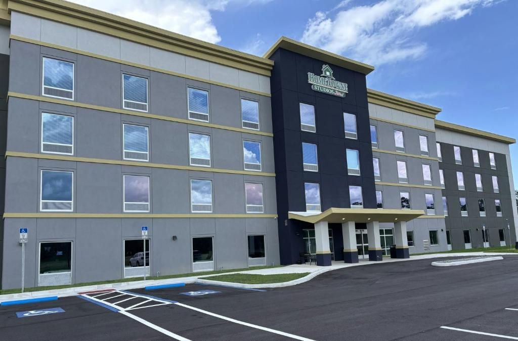 A multi-story hotel with a modern design, featuring a prominent entrance and a parking lot.