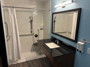 Un baño moderno con ducha, lavamanos, espejo y toallero.