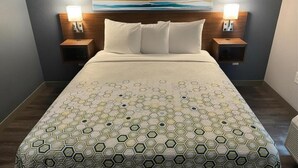 A hotel room with a large bed, two bedside tables with lamps, a headboard, and a painting on the wall. - Hometownestudios Bradenton (Bradenton)
