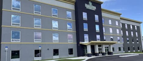 A multi-story hotel with a modern facade, a covered entrance, and a parking lot with handicapped parking spaces.