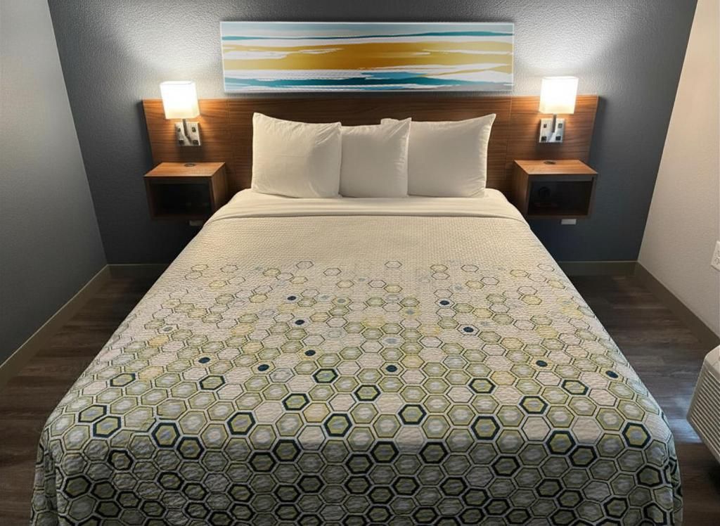 Ein Hotelzimmer mit einem großen Bett, zwei Nachttischen mit Lampen, einem Kopfteil und einem Bild an der Wand.
