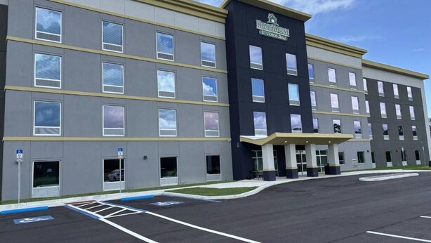 A multi-story hotel with a modern design, featuring a prominent entrance and a parking lot. - Hometownestudios Bradenton (Bradenton)