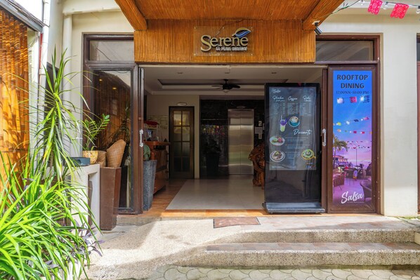 Der Eingang zu einem Restaurant mit einem Schild, auf dem 'Serene La Playa Brisa' steht, und einer Speisekarte, die 'Rooftop Dining' von 12:00 bis 22:00 Uhr bewirbt.