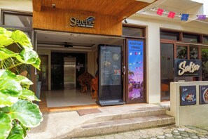 Entrada a un restaurante con un letrero que dice 'Serene La Playa Boracay' y un tablero de menú que anuncia 'Comida en la terraza' con horario de atención.