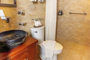 A bathroom with a toilet, a glass shelf, a wooden basin, and a marble wall. - Serene La Playa (Malay)